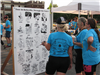 Three women in blue Tour de Belleville t-shirts looking at past event photos