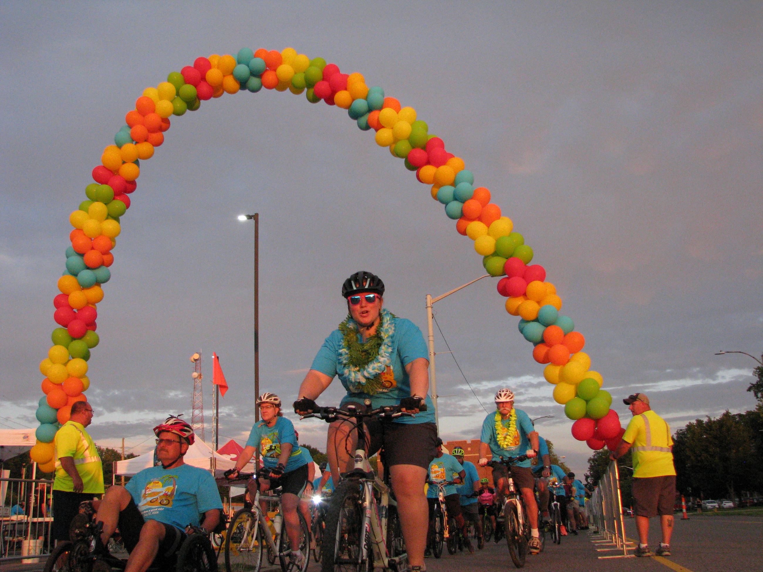 Many bike riders start the Tour de Belleville under a balloon archway