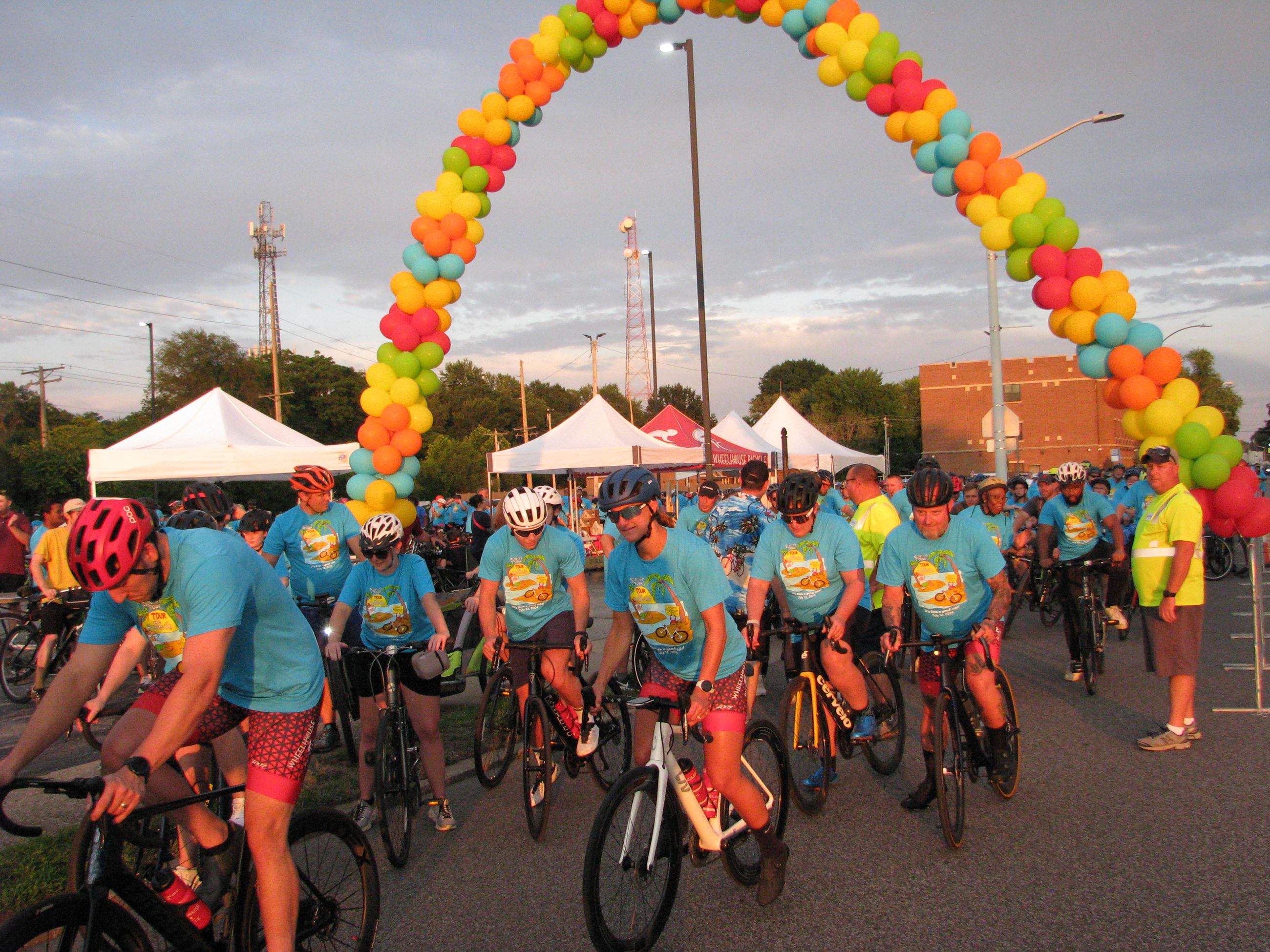 Bike riders begin the Tour de Belleville under a balloon archway 