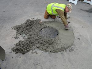 Man Repairing Concrete Around Manhole Cover
